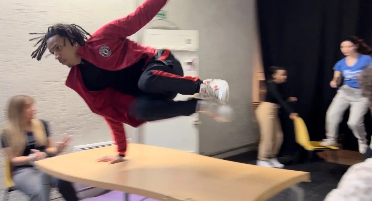 Un comédien franchit une table en saut pendant un stage